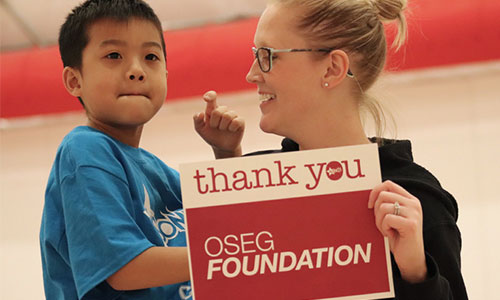 woman and young boy holding a sign saying Thank you OSEG Foundation